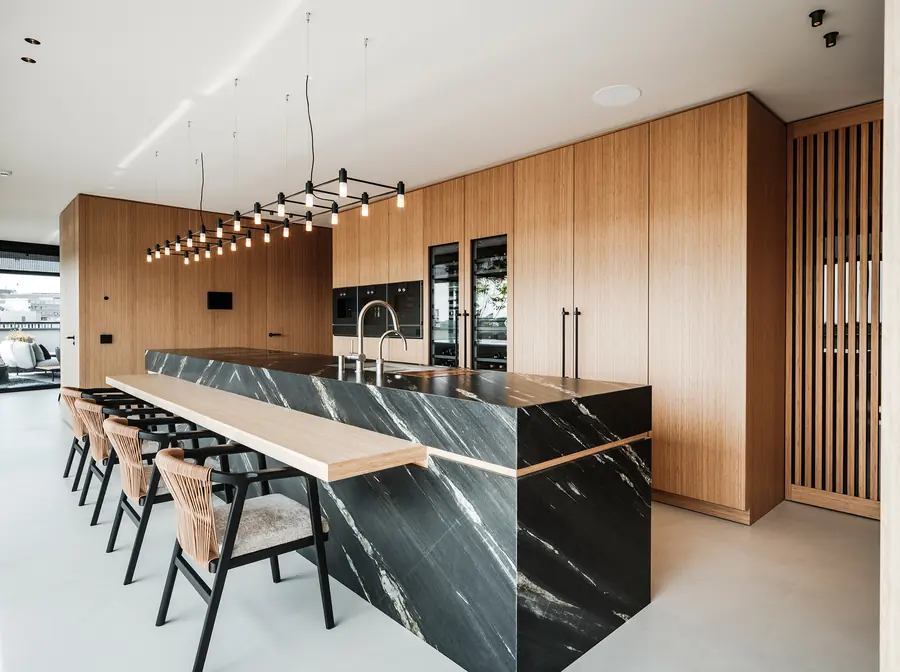 Penthouse-keuken met meterslang kookeiland van donker kwartsiet en wanden van bamboehout