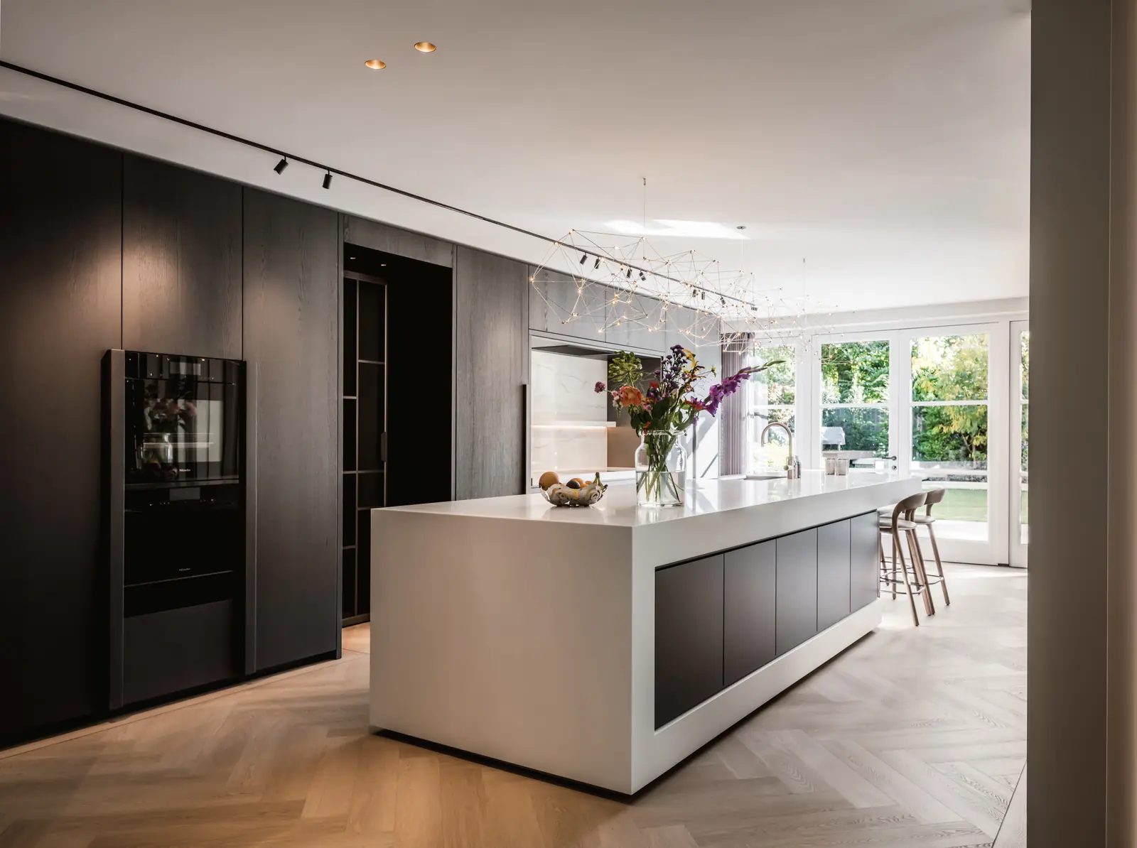 Moderne design keuken met een wit eiland van Corian en een kastenwand in donker eiken